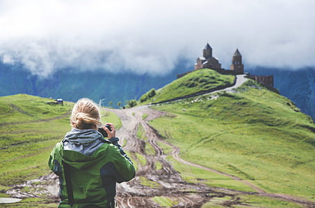 girl taking picture of green land thumbnail
