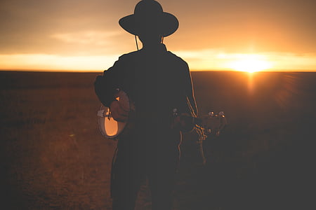 silhouette of person playing stringed instrument during sunset thumbnail
