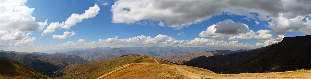 brown road mountain under blue and white cloudy sky thumbnail