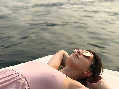 woman lying on white surface near body of water thumbnail