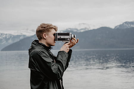 man using digital telescope near body of water during daytime thumbnail
