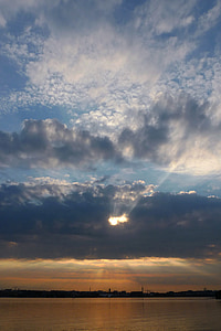 sun covered by cumulus clouds over body of water thumbnail