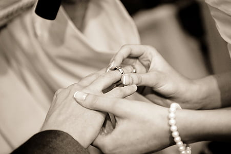 grayscale photography of person holding silver-colored wedding ring thumbnail