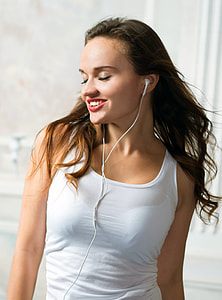 woman wearing white tank top and white earphones standing inside well lighted room thumbnail