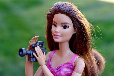 selective focus photography of blonde-haired female doll holding video camera thumbnail