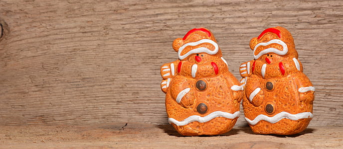 two brown-and-white snowman figurines on brown wooden surface thumbnail