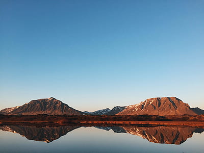 landscape photography of brown mountains with body of water under clear blue sky thumbnail