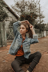 woman sitting on pavement near gate under cloudy sky thumbnail
