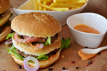 double hamburger sandwich beside a bowl of mustard thumbnail