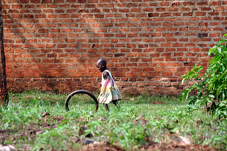 girl playing with tire beside brown brick wall thumbnail
