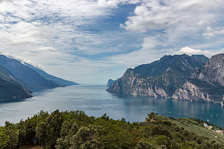 Green Trees Near Large Body of Water Across Mountains during Daytime thumbnail