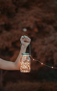 person holding clear glass mason jar with string lights thumbnail