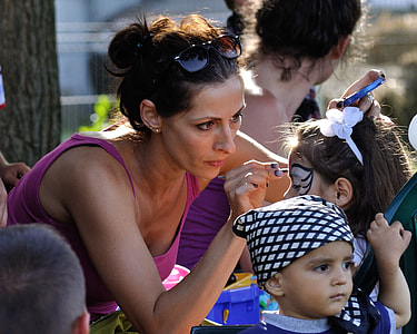 girl holding brush while doing painting the face of the girl on outdoors thumbnail