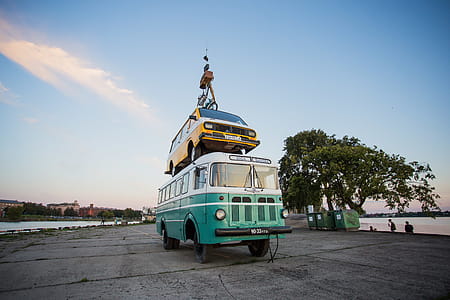 Teal Bus With Yellow Car on Roof thumbnail