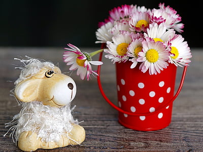 daisy flowers in red and white steel pot beside ceramic sheep figurine thumbnail