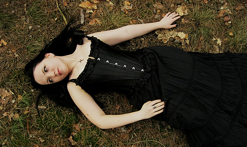 woman in black sleeveless dress lying on green grass field thumbnail