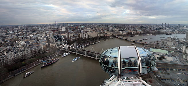 people inside glass Ferris wheel with body of water and buildings view at daytime thumbnail