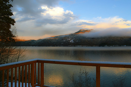 red wooden handrails across lake and mountain during cloudy daytime thumbnail
