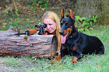 woman sighting gun beside adult Doberman pinscher thumbnail