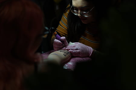 woman in orange and white striped sweater doing tattoo thumbnail