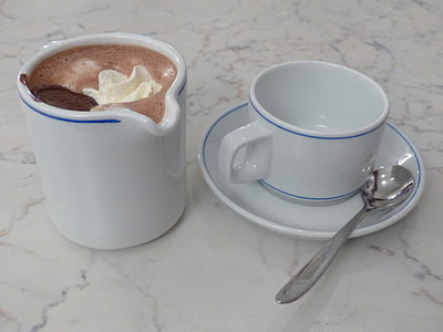 white ceramic mug with chocolate drink beside coffee mug with spoon on white surface thumbnail