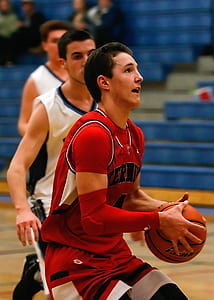 A Man Wearing Red Jersey Carrying an Orange Basketball thumbnail