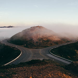splitting road surrounding brown mountain under clear sky during daytime thumbnail