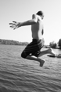 grayscale photo of boy jump through water thumbnail