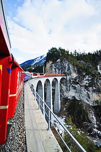red and white train entering tunnel under blue cloudy skies thumbnail