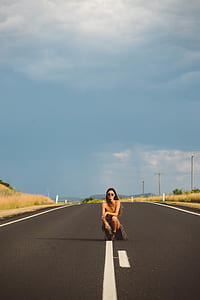 woman sitting on white line open road thumbnail
