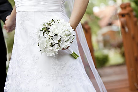 person wearing white dress while holding white petaled flower bouquet thumbnail
