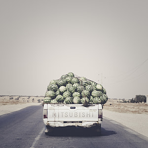 Mitsubishi pickup truck carrying watermelon lot traveling on road during daytime thumbnail