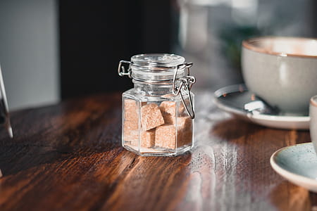 Clear Condiment Shaker With Brown Sugar Cubes Near Gray Teacup thumbnail
