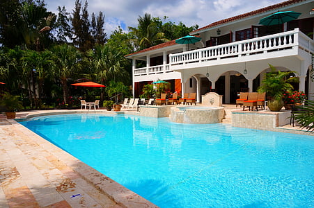 white concrete house beside swimming pool and green trees thumbnail