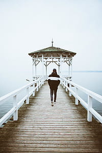 person walking towards wooden dock during daytime thumbnail
