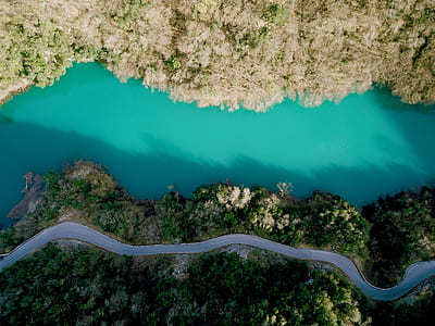 aerial view of road near trees and body of water thumbnail