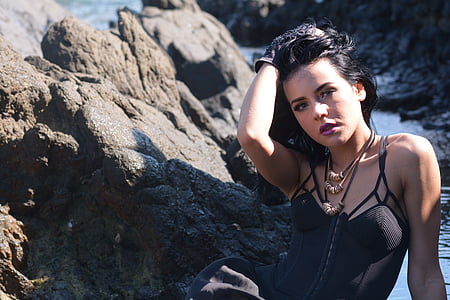 shallow focus photography of woman sitting beside rock boulder thumbnail