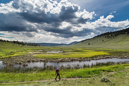 man walking on trail near river thumbnail