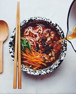 brown wooden chopsticks on top of black and white ceramic bowl thumbnail