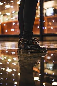 Photo of Person Wearing Black Fitted Jeans and Black Dr.martens Boots Standing on Black Floor Tiles thumbnail