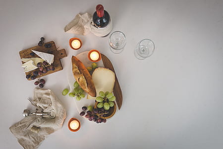 flat lay photography of wine bottle beside glasses and chopping board thumbnail