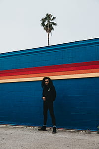 man wearing black top and pants near blue paint wall thumbnail