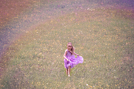 girl wearing purple dress running on grass field thumbnail