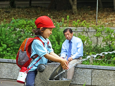 girl in school uniform washing her hands near sitting man thumbnail
