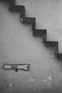 Grayscale Photo of Exit Signage Under Brown Stairs thumbnail