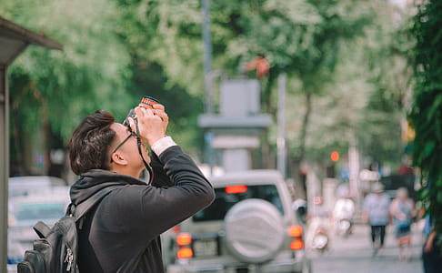 Man Wearing Black Hoodie Holding Dslr Camera Shooting on Upper Direction thumbnail