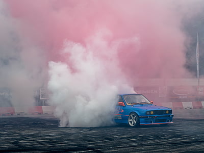 photo of blue car drifting on roadway with smoke at the back thumbnail