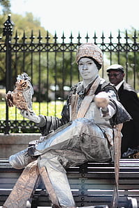 male outdoor entertainer sitting on black bench thumbnail