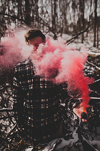 man wearing long-sleeved shirt holding pink smoke near trees thumbnail