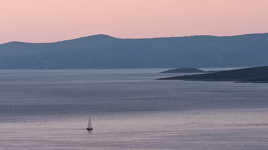 black and white sailboat sailing on body of water near mountains at sunset thumbnail